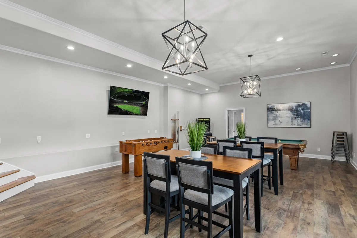 A bright, inviting room featuring a pool table and foosball table positioned near a dining table, with a wall-mounted TV creating a sports bar-like atmosphere. The setup is perfect for both spirited games and shared meals, enhancing the sense of togetherness.