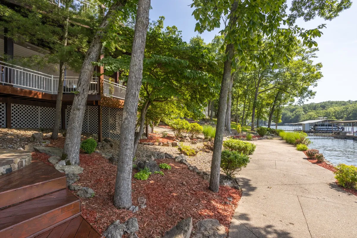 An inviting exterior shot showcasing a landscaped path with wooden steps, surrounded by lush greenery and leading directly to the serene waterfront. The area looks ideal for strolls, play, and outdoor relaxation—activities that are perfect for guests and their furry friends.