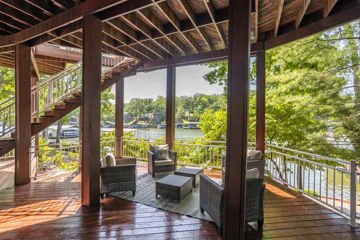 A tranquil exterior view featuring a spiral staircase, a cozy sitting area, and a peaceful water view framed by lush greenery. The scene is inviting for relaxation and quiet moments, with direct access to nature and the outdoors.