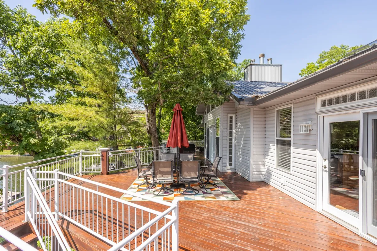A wooden deck with a red umbrella covers an inviting outdoor dining area set amidst vibrant greenery. The space is arranged for al fresco meals, social gatherings, or quiet relaxation with nature as the backdrop, reflecting the communal and pet-friendly spirit of the lodge.